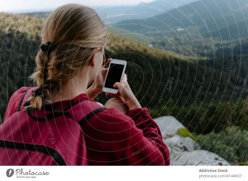 Weibliche Rucksacktouristin benutzt ihr Smartphone, während sie sich auf einem Berggipfel ausruht Frau Wanderung Berge u. Gebirge benutzend reisen Aktivität