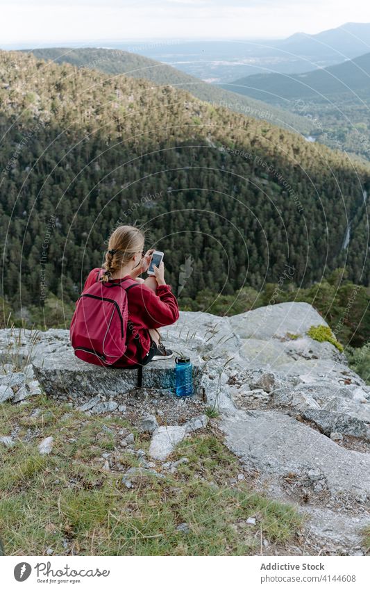Weibliche Rucksacktouristin benutzt ihr Smartphone, während sie sich auf einem Berggipfel ausruht Frau Wanderung Berge u. Gebirge benutzend reisen Aktivität