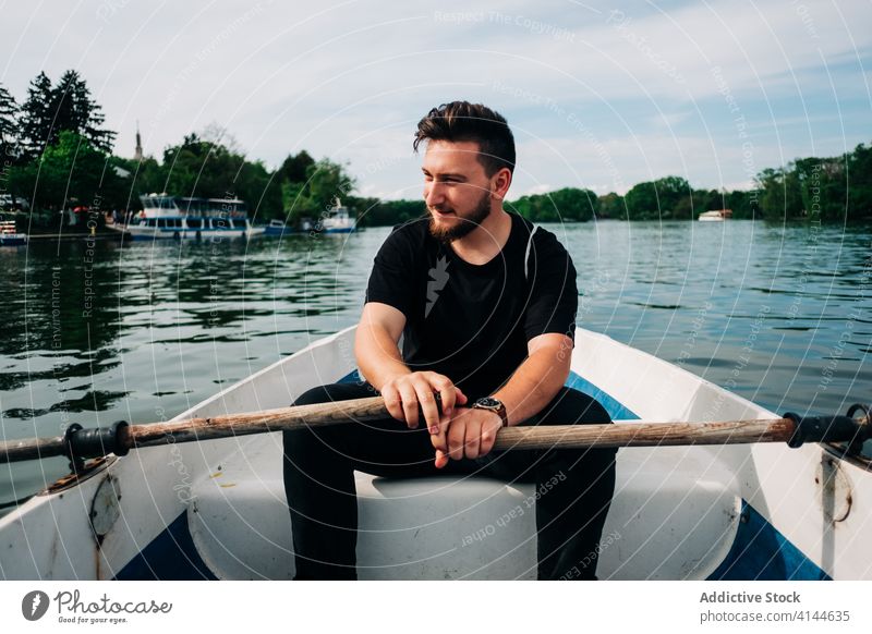 Zufriedener Mann rudert Boot auf friedlichem Teich Rudern See positiv Natur Aktivität Inhalt malerisch Windstille sich[Akk] entspannen Sommer Freizeit