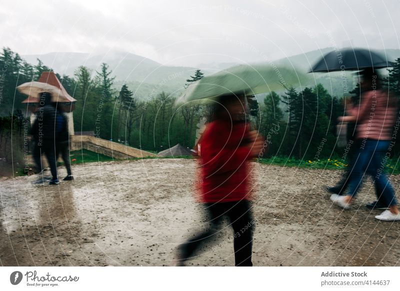 Unbekannte Menschen mit Regenschirmen auf einer Bergkuppe Spaziergang Landschaft Hochland Grün malerisch Natur bedeckt Wetter Tourismus reisen grün