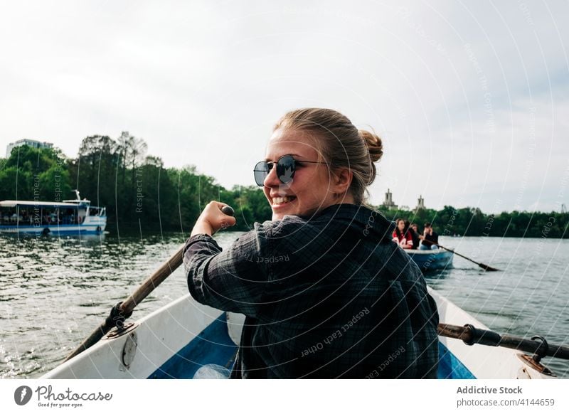 Fröhliche Frau rudert auf einem Boot auf dem See Rudern positiv heiter sculling Lächeln Natur Aktivität friedlich Windstille sich[Akk] entspannen Sommer Glück