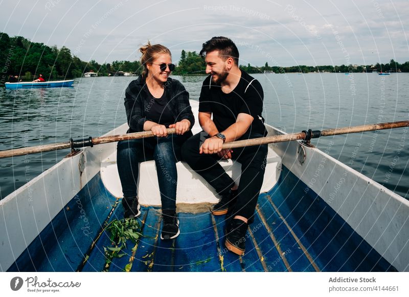 Fröhliches Paar rudert Boot zusammen auf malerischem See Rudern Teich Zahnfarbenes Lächeln heiter Natur Zusammensein schön Partnerschaft sorgenfrei Aktivität