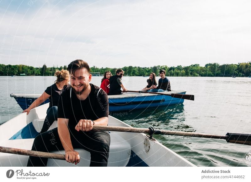 Glückliche Freunde, die sich auf Booten vergnügen und ihr Smartphone benutzen Teich benutzend Lachen positiv Natur Freundschaft Aktivität malerisch Browsen jung