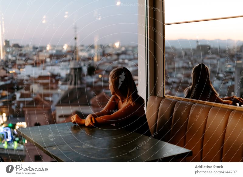 Junge Frau genießt das Stadtbild vom Café aus Dachterrasse Großstadt Fenster Abend Madrid Sonnenuntergang gemütlich urban Spanien Glaswand Komfort