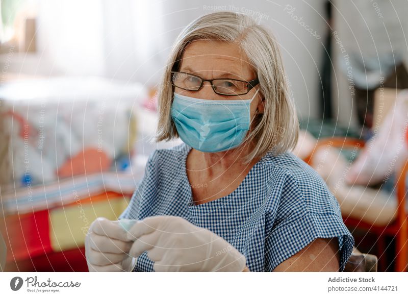 Näherin hält Stoff mit Schere Coronavirus Mundschutz nähen Gewebe Frau Kunstgewerbler COVID handgefertigt Pandemie behüten selbstgemacht verhindern COVID19