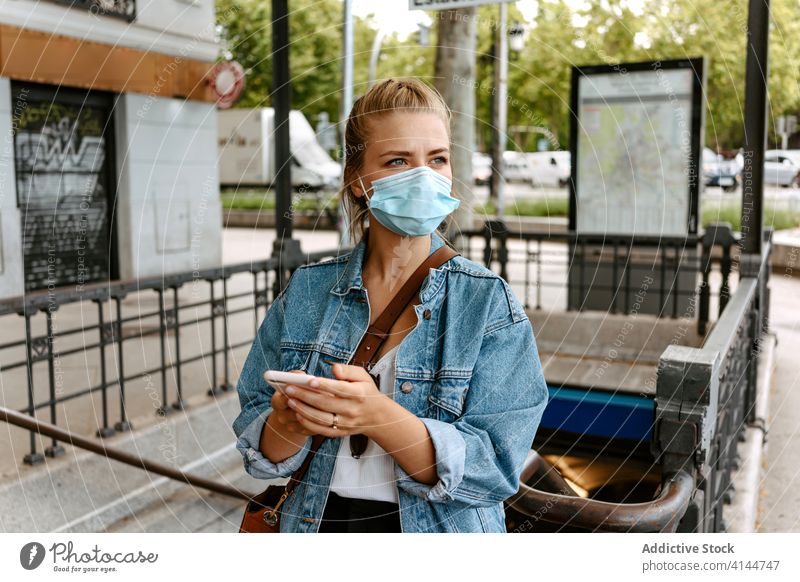 Junge Frau mit Maske und Smartphone geht eine Treppe hinauf auf die Straße Mundschutz Großstadt U-Bahn benutzend urban Coronavirus neue Normale Lifestyle