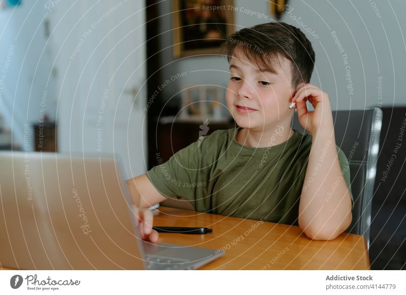 Fokussiertes Kind benutzt Laptop zu Hause Junge Tippen Tisch heimwärts benutzend Internet Gerät Apparatur Browsen online Anschluss wenig lässig Kindheit klug