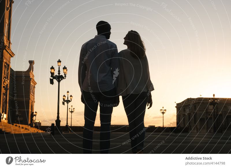 Romantisches multiethnisches Paar hält Händchen und schlendert durch die Stadt Spaziergang Händchenhalten romantisch sorgenfrei Partnerschaft Straße Zuneigung
