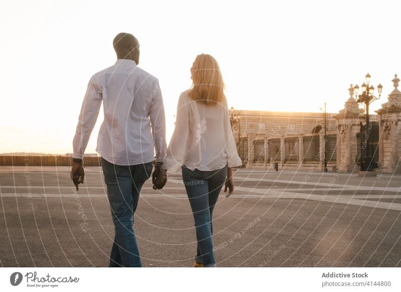 Romantisches multiethnisches Paar hält Händchen und schlendert durch die Stadt Spaziergang Händchenhalten romantisch sorgenfrei Partnerschaft Straße Zuneigung