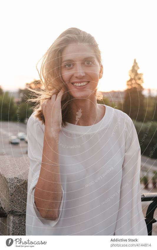 Fröhliche Frau stützt sich lachend auf das Geländer des Bürgersteigs freudig ruhen Lachen Reling expressiv heiter Zahnfarbenes Lächeln urban genießen