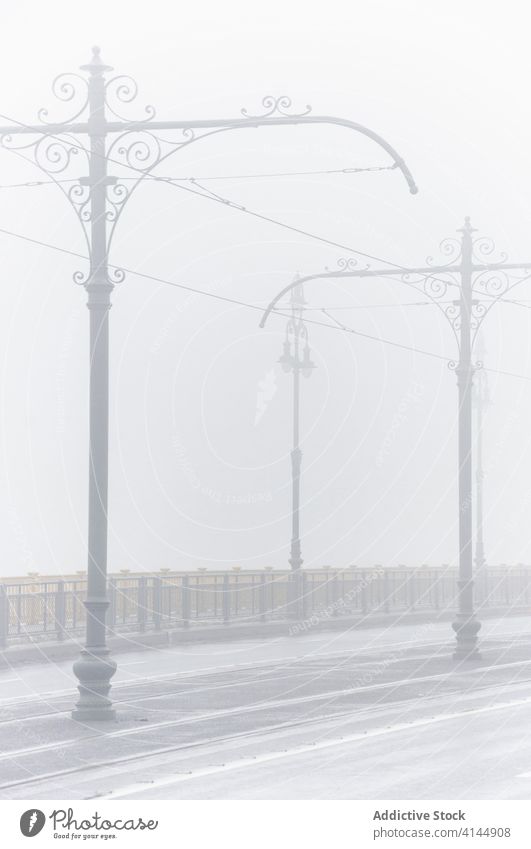 Leere Straße an einem nebligen Tag Nebel Morgen Großstadt leer trist Ständer Kabel Fahrbahn Metall Zaun alt verwittert erstaunlich Wetter Dunst ruhig prunkvoll