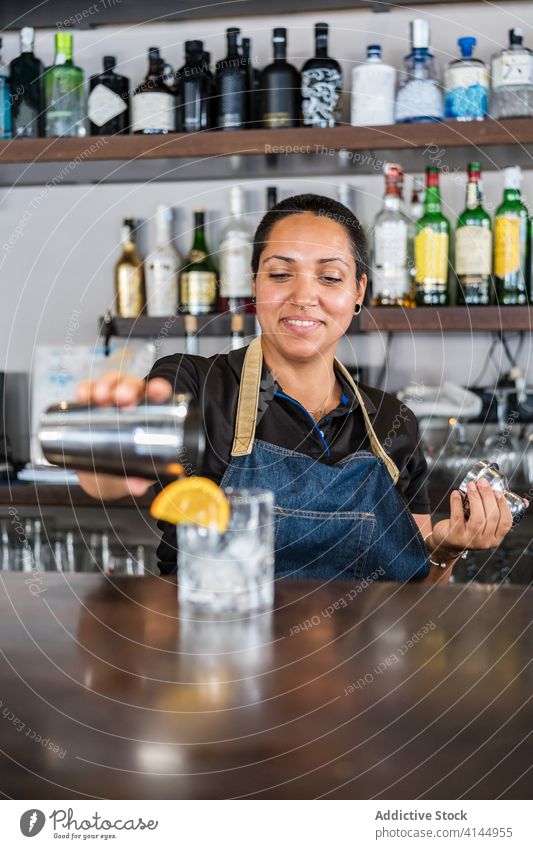 Fröhlicher ethnischer Barkeeper in einem Cafe Frau Abfertigungsschalter Café positiv Alkohol trinken Barkeeperin Dienst Getränk professionell Glück Lächeln