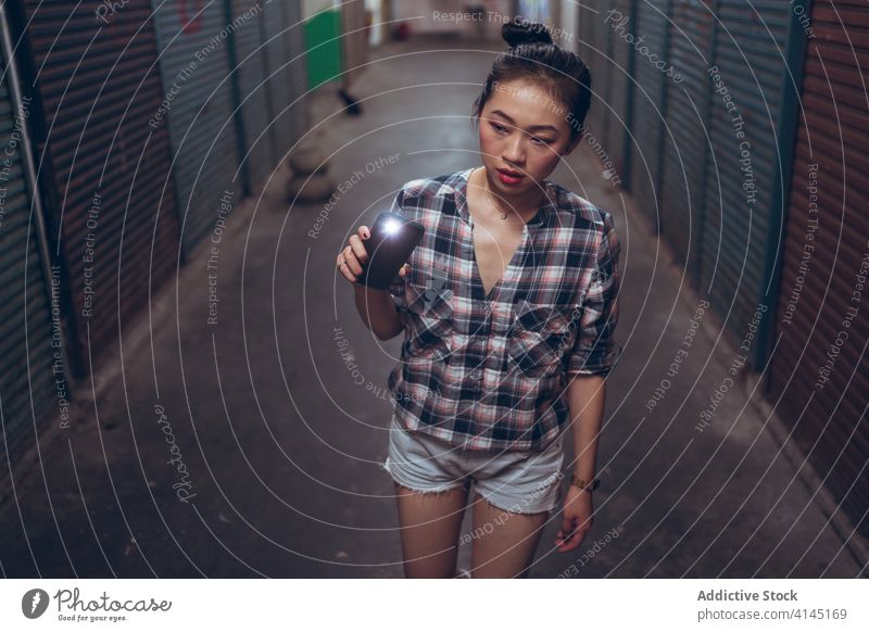 Junge Frau mit Taschenlampe geht in unterirdischer Halle Vorsicht dunkel Gang Durchgang eng jung Spaziergang asiatisch ethnisch behutsam Licht leuchten