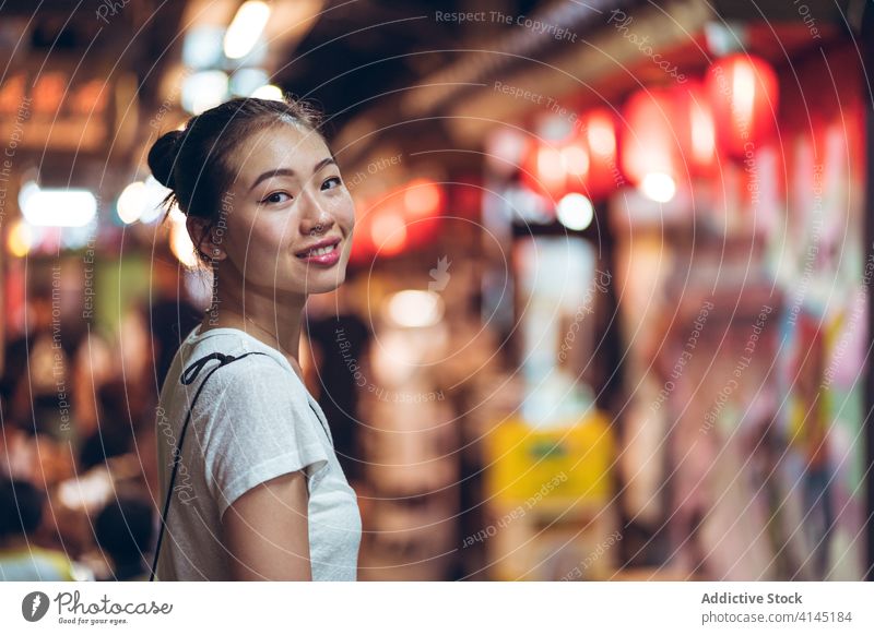 Fröhliche ethnische Frau in der Nacht Stadt Glück Lächeln Großstadt Straße jung positiv heiter urban froh Freude asiatisch lässig Lifestyle leuchten Abend