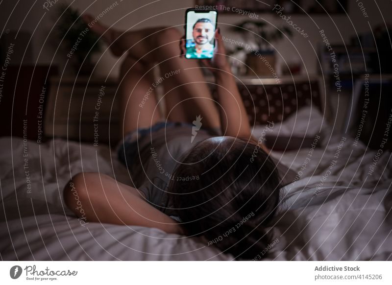 Frau führt Videochat mit ihrem Freund auf dem Smartphone im Bett Freundin Video-Chat Videoanruf Gespräch heimisch benutzend Gerät Apparatur Funktelefon