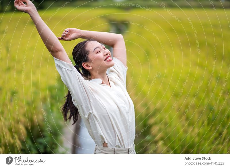 Unbeschwerte Frau auf grüner Wiese sorgenfrei genießen Freiheit Sommer Feld Natur Reis Lächeln ruhig asiatisch ethnisch Glück ruhen Optimist positiv froh stehen