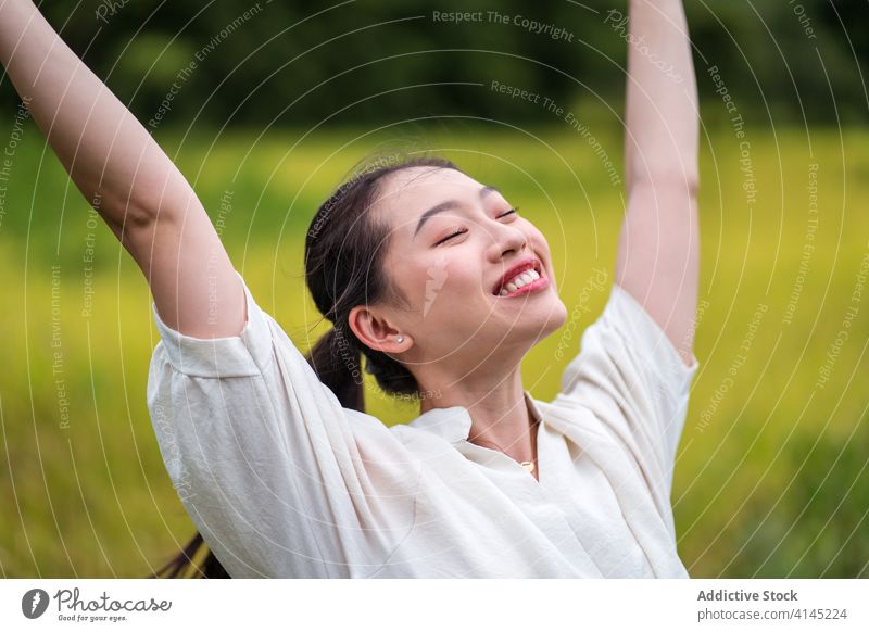 Unbeschwerte Frau auf grüner Wiese sorgenfrei genießen Freiheit Sommer Feld Natur Reis Lächeln ruhig asiatisch ethnisch Glück ruhen Optimist positiv froh stehen