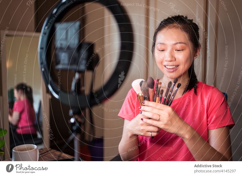 Schönheitsbloggerin zeigt Pinsel für Make-up vlog Blogger Frau Bürste Kosmetik Aufzeichnen Video manifestieren positiv jung asiatisch ethnisch zeigen Lächeln
