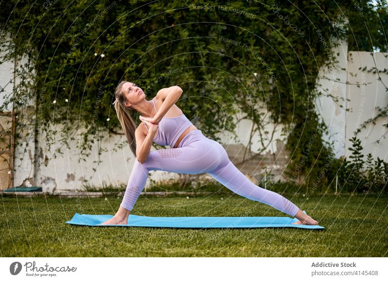Ruhige Frau beim Yoga in Parivrtta Anjaneyasana parivrtta anjaneyasana Pose gedrehte Sichellonge Asana Namaste gestikulieren Windstille beweglich