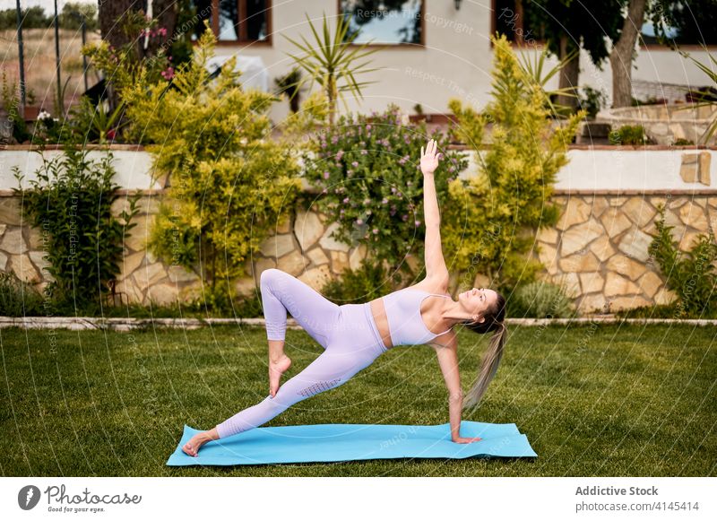 Konzentrierte Frau beim Yoga in Side Plank Pose Seitenbrett vasisthasana beweglich Gleichgewicht Konzentration Sommer aktive Kleidung üben Barfuß Unterlage Hof