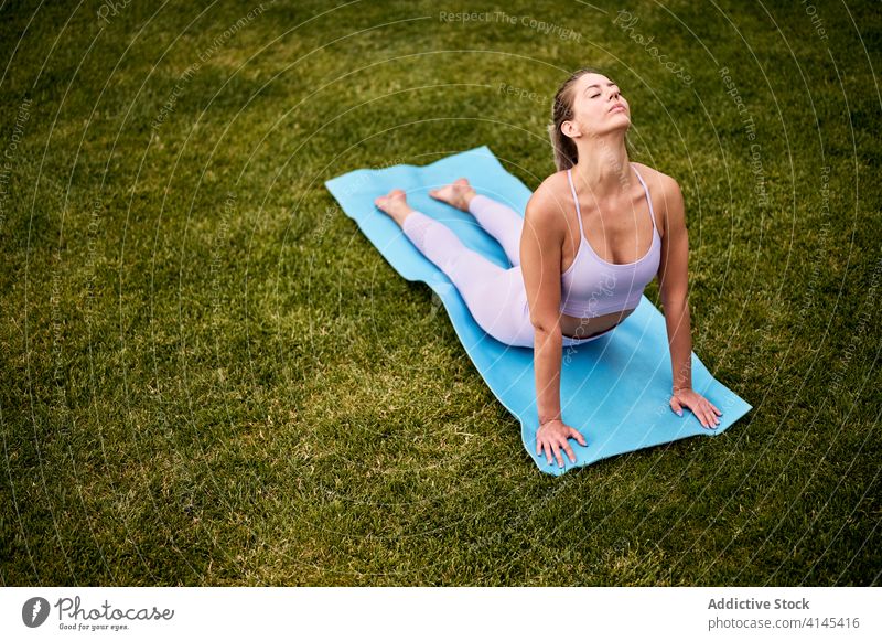 Ruhige Frau macht Yoga in Cobra-Pose Kobra-Pose üben bhujangasana Harmonie Hinterhof Rasen beweglich Asana friedlich Unterlage Augen geschlossen Übung
