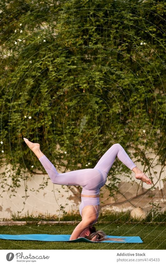 Unerkennbar flexible Frau beim Handstand mit Spagat auf der Matte üben Yoga Gleichgewicht Barfuß Gesundheitswesen Wohlbefinden Harmonie Unterlage Stressabbau