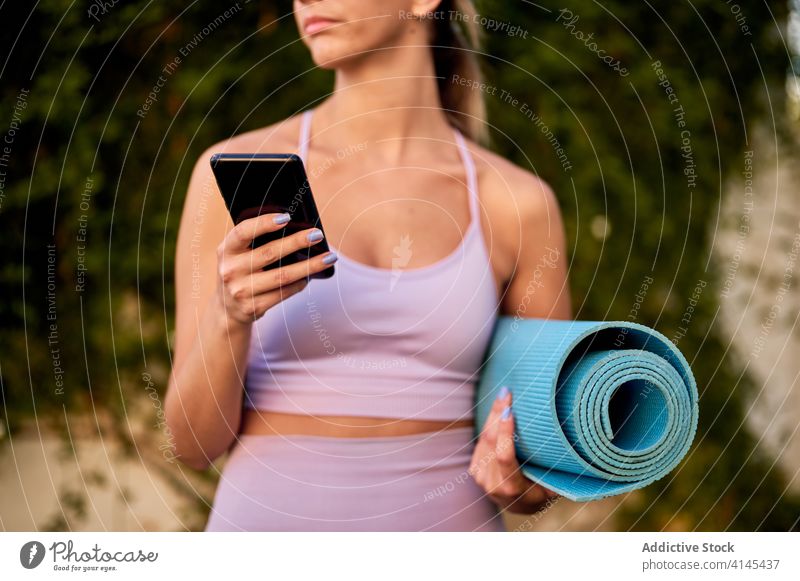 Verträumte Frau mit Smartphone und Yogamatte, die über die Natur nachdenkt Unterlage nachdenken Gesundheitswesen Wohlbefinden Sportbekleidung Harmonie benutzend