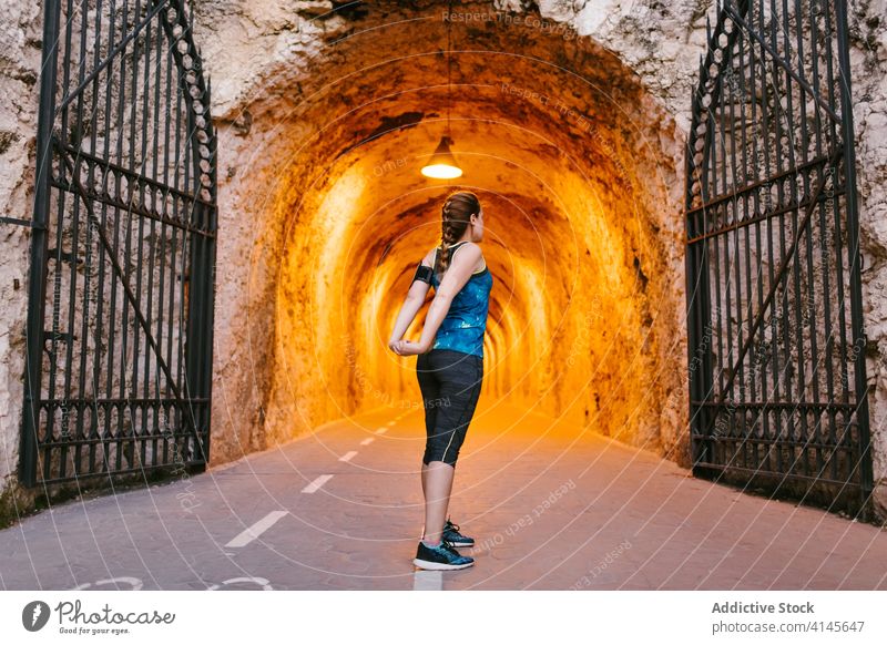 Sportlerin, die während des Trainings im Tunnel die Arme streckt Dehnung Aufwärmen Übung Armbinde Stollen Wand rau Sportbekleidung Athlet Gesundheit passen