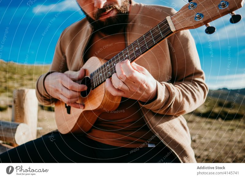 Bärtiger Mann spielt Ukulele auf dem Lande spielen Landschaft Zaun Himmel wolkig Musik puerto de la morcuera Spanien männlich reisen ernst Urlaub Ausflug Natur