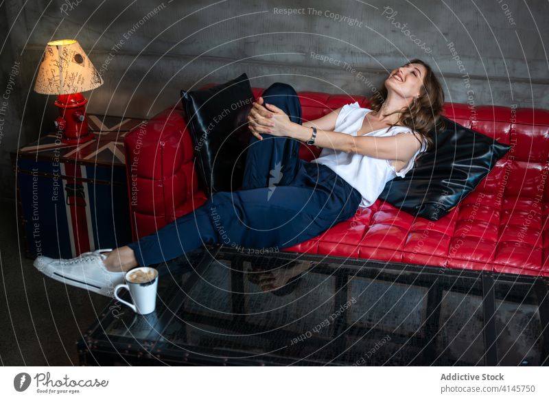 Junge Frau auf Ledersofa liegend Lügen Sofa ruhen Stil heiter Komfort gemütlich sich[Akk] entspannen Glück trendy modern jung Liege kreativ Design Innenbereich