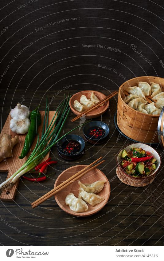 Chinesische gedämpfte Knödel xiaolongbao jiaozi chinesisches Essen Lebensmittel lecker Holz dunkle Speisen Gemüse Salatbeilage Salatgurke Verdunstung