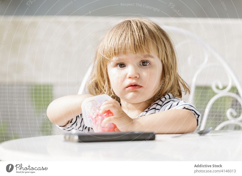 Kleines Mädchen isst Gelee im Hinterhof lutschen Finger Kind essen dreckig lustig bezaubernd Götterspeise süß Dessert Vergnügen geschmackvoll wenig Tisch
