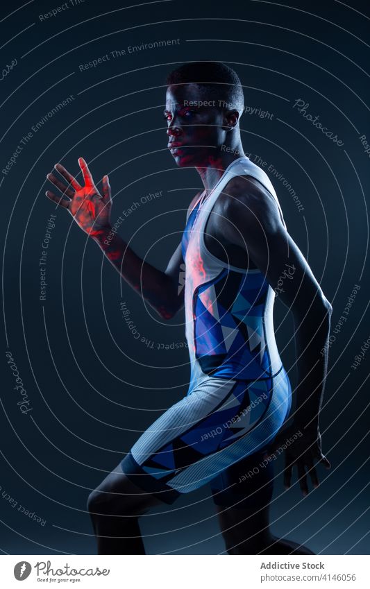 Muskulöser männlicher Läufer im Studio mit Neonlicht Mann Athlet Sportler Bestimmen Sie selbstbewusst aktiv physisch neonfarbig jung schwarz Afroamerikaner