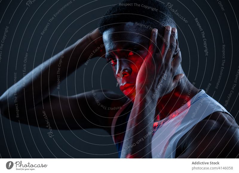 Selbstbewusster schwarzer Sportler in Neon-Beleuchtung Athlet selbstbewusst brutal Herausforderung wettbewerbsfähig Mann Bestimmen Sie Porträt neonfarbig rot