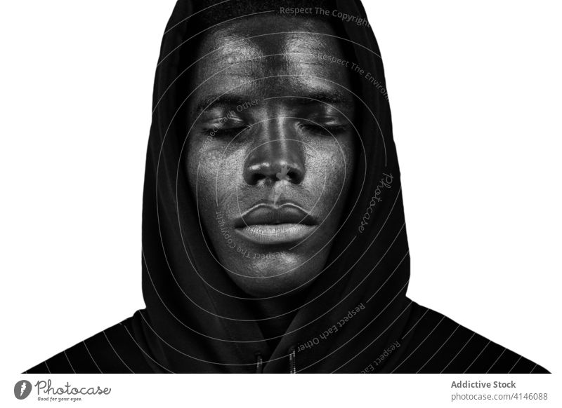 Schwarzer Mann mit Kapuze im Studio schwarz Kapuzenpulli jung Augen geschlossen emotionslos Windstille modern Porträt männlich Afroamerikaner ethnisch Kopf