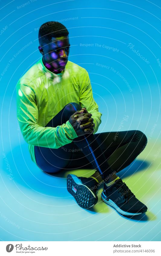 Ethnischer Sportler in trendiger Sportkleidung im Studio Athlet Sportbekleidung Trainingsanzug Outfit Mode Läufer Mann aktiv Sprinter Jogger neonfarbig jung