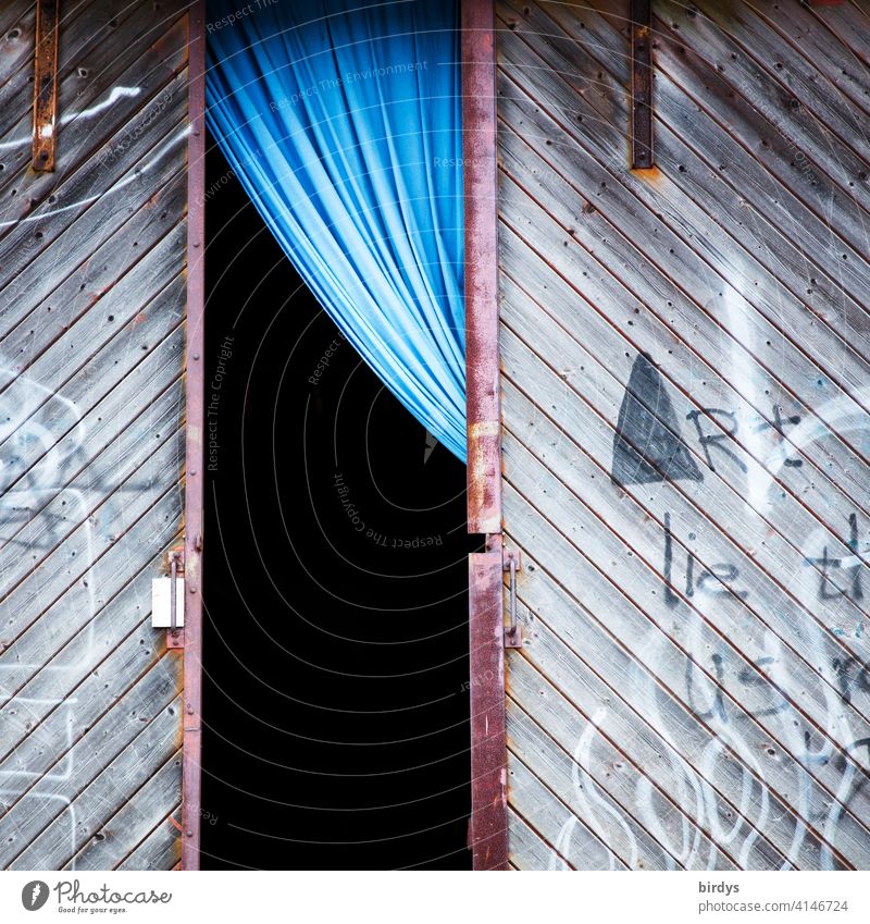 geöffnetes Lagerhallentor mit unerwartet edlem blauen Vorhang Tor Eingangstor Schiebetor Holztor grau einladend offen gegensätzlich Location Stil Öffnung