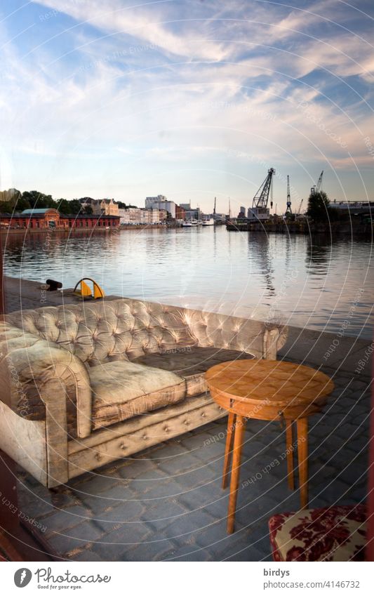 Illusion l Spiegelung in einer Fensterscheibe am Lübecker Hafen, Couch und Couchtisch am Kai des Hafens Täuschung Surrealismus Sofa Himmel Hafenflair Irritation