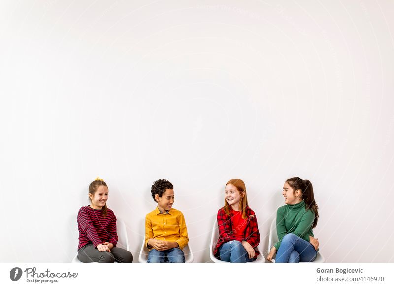Porträt der niedlichen kleinen Kinder in Jeans sitzen in Stühlen gegen weiße Wand bezaubernd Junge lässig Kaukasier Kindheit Kleidung Jeansstoff Ausdruck Mode