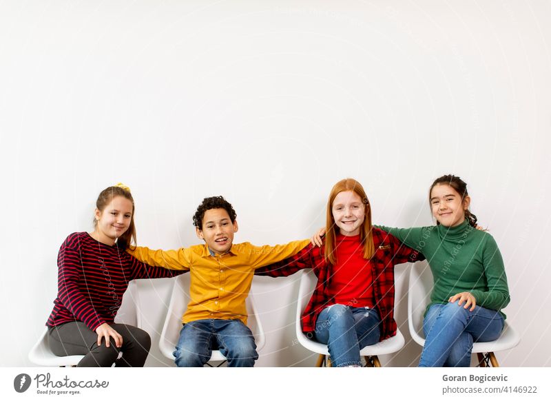 Porträt der niedlichen kleinen Kinder in Jeans sitzen in Stühlen gegen weiße Wand bezaubernd Junge lässig Kaukasier Kindheit Kleidung Jeansstoff Ausdruck Mode