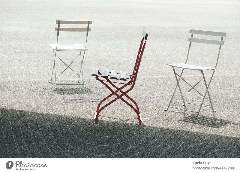 2x Schneeweißchen und 1x Rosenrot: drei Klappstühle mitsamt ihrer Schatten stehen in der Sonne, zwei davon weiß und einer rot. Stühle Stuhl Klappstuhl Frühling