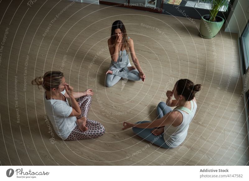 Ruhige Yogalehrerinnen üben gemeinsam Pranayama Frauen Atem Übung Klasse Lotus-Pose meditieren Wellness Asana Gesundheit Menschengruppe Sportbekleidung