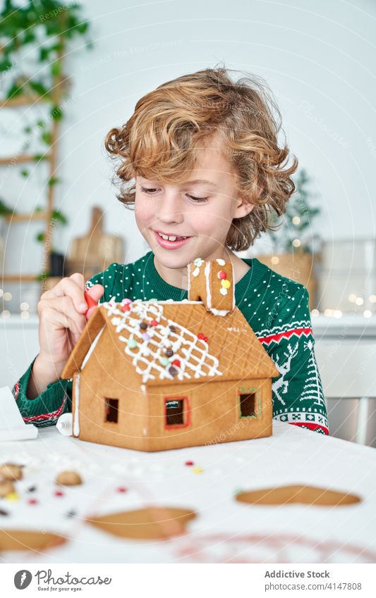 Kleiner Junge beim Verzieren von Lebkuchenhäusern Kind Haus Weihnachten Zuckerguß vorbereiten machen dekorieren heimwärts Küche wenig Winter festlich Feiertag