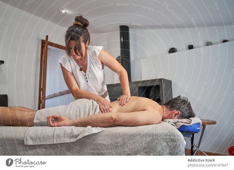 Masseurin massiert den Rücken eines entspannten Kunden Massage Salon Frau kneten Körper Pflege Gesundheit Therapeut Klient Tisch Therapie geduldig ruhig Spa