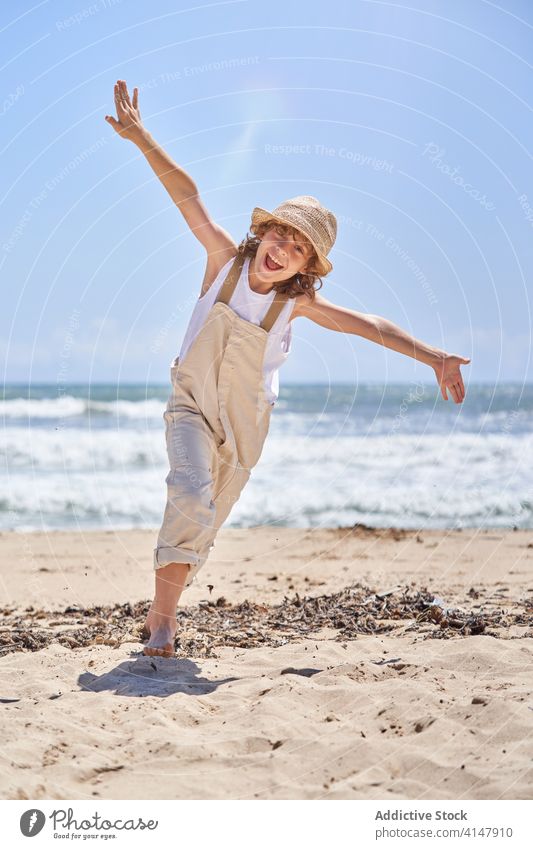 Glücklicher Junge läuft mit ausgestreckten Armen am Sandstrand laufen Spaß haben Euphorie Aufregung Kind aktiv Arme ausgestreckt schreien Seeküste Sommerzeit