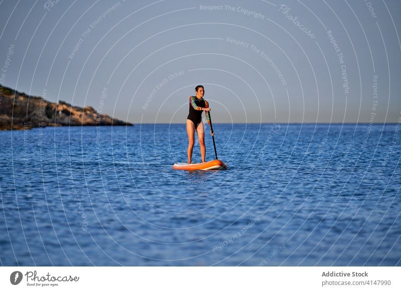 Fit Frau schwimmt auf Paddleboard im Meer Paddelbrett Brandung Surfer Reihe üben passen schlank Badeanzug Surfen Holzplatte Aktivität Surfbrett Sport Urlaub