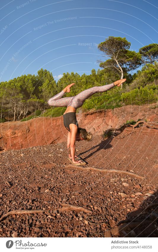 Blonde Frau übt eine Variation der Handstand-Yoga-Pose in der Mitte des Waldes natürlich Strumpfhose Invers Fitness Sport Stärke Gesundheit Mädchen Athlet Übung