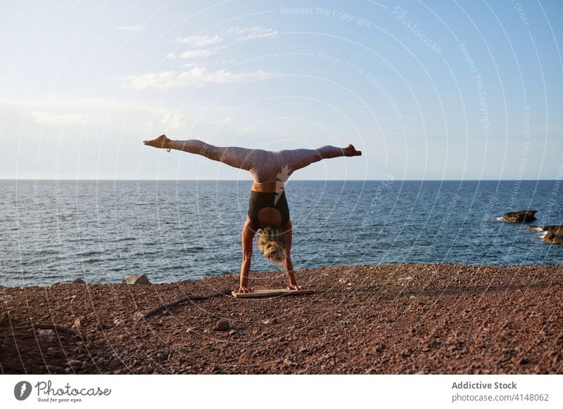 Frau, die den Handstand Yoga Position vor dem Meer Licht vertikal Dreieck Strand MEER vereinzelt Fitness Sport Stärke Gesundheit Mädchen Athlet Übung Pose stark