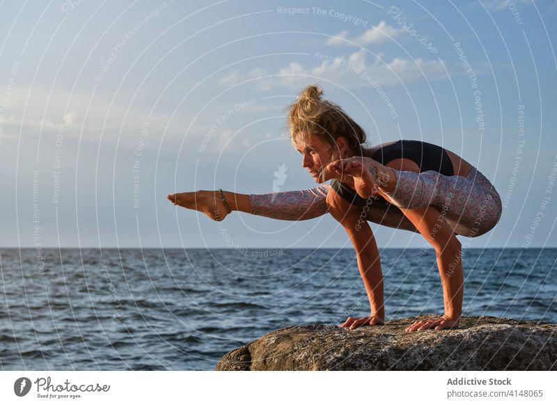 Frau auf einem Felsen mit Blick aufs Meer bei einer Variation der Handstand-Yoga-Pose Konzentration Stärke copyspace anheben Strand MEER vereinzelt Fitness
