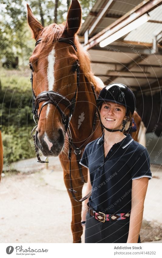 Inhalt Jockey mit Pferd auf Ranch Reiterin Zaumzeug Frau vorbereiten Tier Zügel Lächeln Zusammensein Werkzeug Gerät pferdeähnlich jung Konzentration ernst